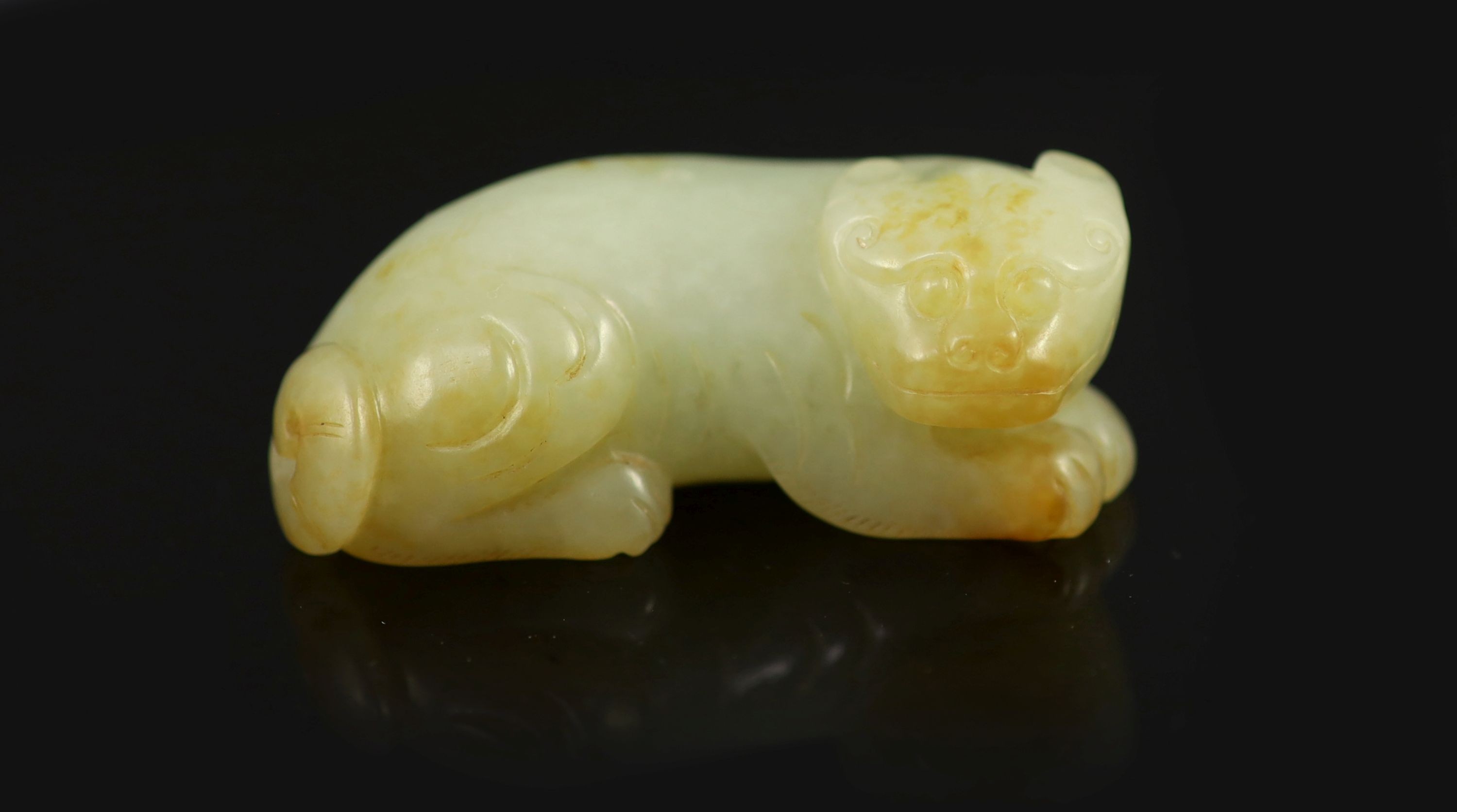 A Chinese pale celadon and russet jade figure of a lion dog, 6.2 cm long
